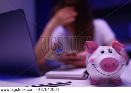 Close-up Of Piggy Bank On Desk, Broken Woman Count Money On Background. Saving Up For Tomorrow, Pay 