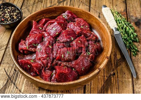 Raw Cut Wild Venison Meat For A Goulash In A Wooden Plate. Wooden Background. Top View