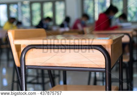 Class Room Tables And Chairs With Paper Documents Of Exam Test On Desk In Examination School While B