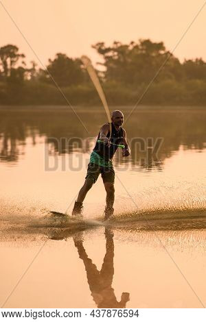 Athletic Man Engaged In Water Sport And Balancing On Water Surface On A Wakeboard