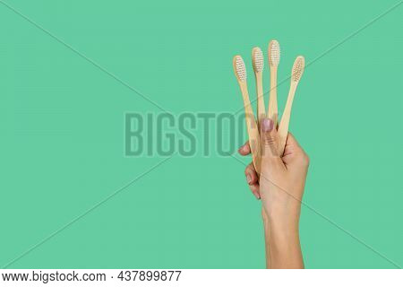 Bamboo Toothbrushes In A Female Hand On A Mint Background With A Place For The Text. Current Trends 