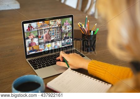 Caucasian woman using laptop for video call, with diverse elementary school pupils on screen. communication technology and online education, digital composite image.