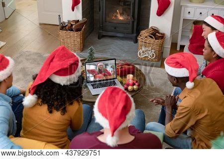 Diverse group of friends making laptop christmas video call with smiling caucasian woman. christmas, festivity and communication technology.