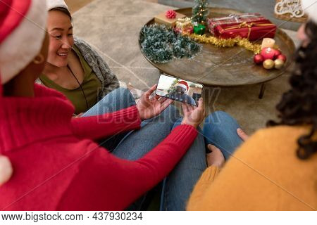 Diverse group of friends making smartphone christmas video call with smiling african american man. christmas, festivity and communication technology.
