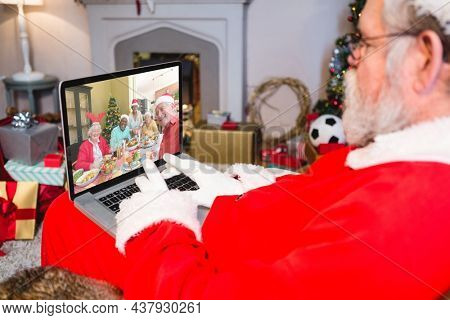 Caucasian santa claus on christmas laptop video call with diverse group of friends. christmas, festivity and communication technology.