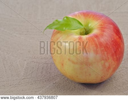 A Large Red Apple With A Leaf Isolated On A Gray Background. Close-up. Space For Text.