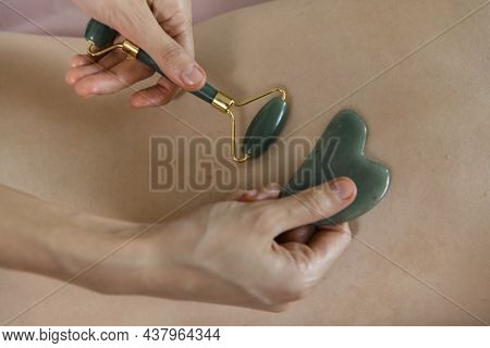 Massage session: woman receiving back Guasha from professional masseur. Attractive caucasian woman h