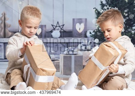 Twin Children At Home Receiving And Opening Christmas Presents.