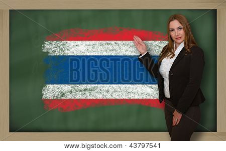 Profesor mostrando la bandera Ofthailand en pizarra para presentación Marketing y publicidad turística