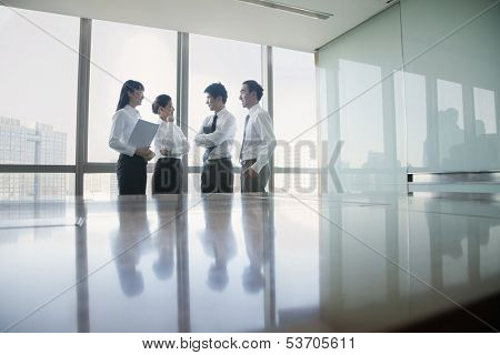 Four young business people standing by conference table