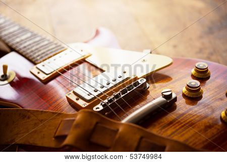 Red sunburst solid body electric guitar with well used leather strap.