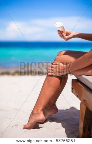 Young Woman Apply Cream On Her Smooth Tanned Legs At Tropical Beac