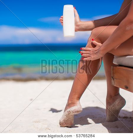 Young Woman Apply Cream On Her Smooth Tanned Legs At Tropical Beac