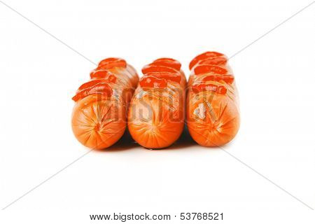 row of sausages with ketchup over white