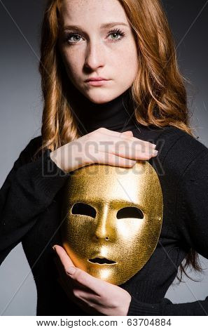 Redhead woman iwith mask in hypocrisy consept against grey background