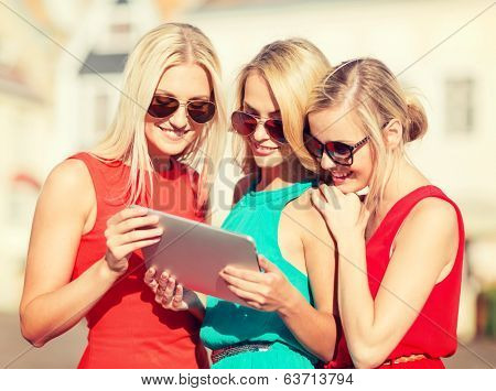holidays and tourism concept - beautiful blonde girls toursits looking into tablet pc in the city