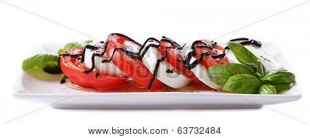 Caprese salad with mozarella cheese, tomatoes and basil on plate, isolated on white