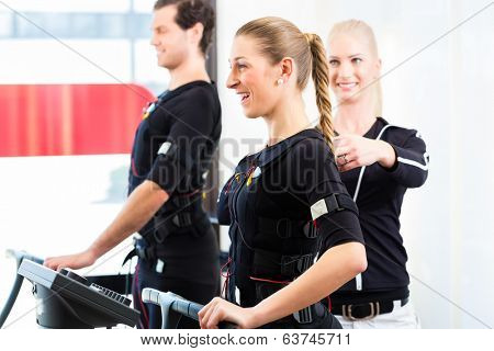 Female coach giving man and woman ems electro muscular stimulation exercise 