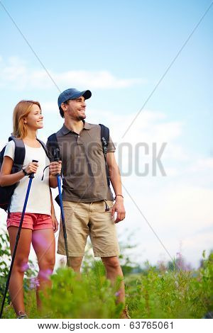 Couple of smiling trippers standing in the countryside at summer