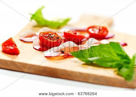 Dried Cherry Tomatoes With Bacon Served On Carving Board. Selective Focus.