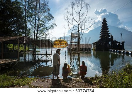 BALI - APRIL 11, 2014: Balinese Hindu devotees go to pray at an ancient temple on Lake Batur, a volcano crater lake in Bali, Indonesia. Religious rituals and ceremonies are a way of life in Bali.