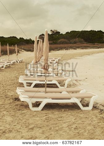 Sunbeds On And Empty Beach At Sunset. Spain.