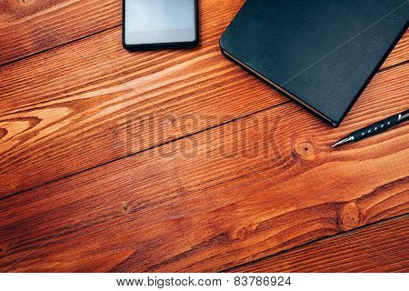 smartphone and notepad on wooden table