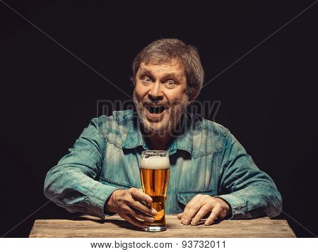 The smiling man in denim shirt with glass of beer
