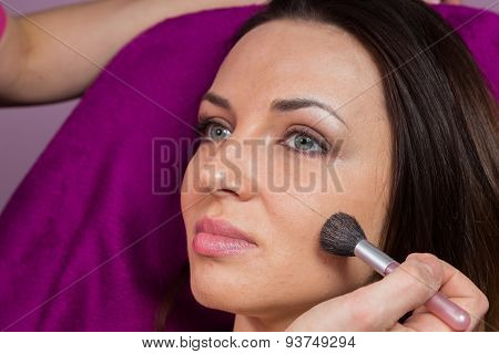 Makeup artist apply makeup on the face of the girl model.