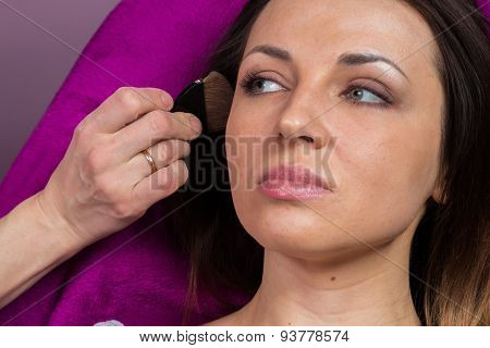 Work of make-up artist. Makeup artist apply makeup on the face of the girl model.