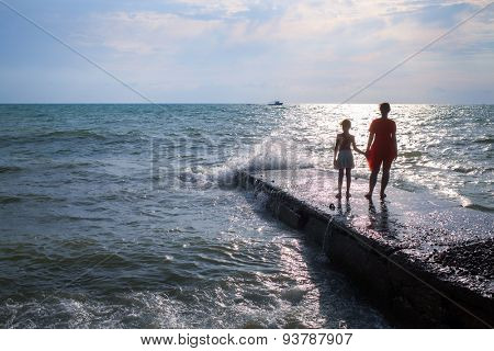 mother and daughter looking at the sea from the pier