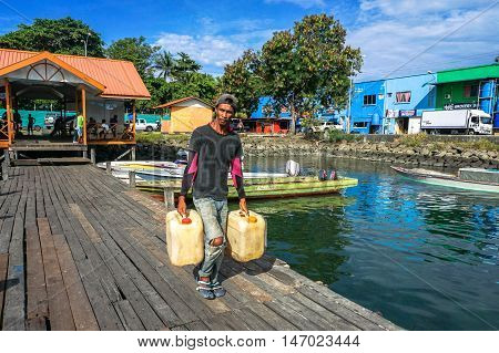 Semporna,Sabah-Sep 10,2016:Boatman with gallons petrol ready to island at Semporna jetty.Its a gateway for vacation,diving & snorkeling trips to the islands of Sipadan,Mabul,Mataking,Maiga & others