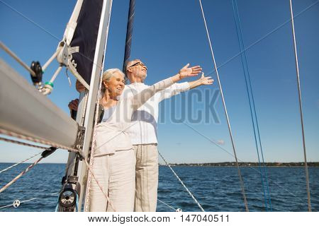 sailing, age, tourism, travel and people concept - happy senior couple hugging on sail boat or yacht deck floating in sea