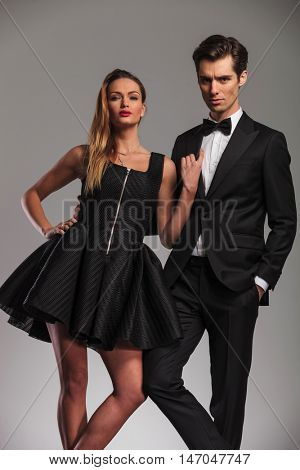 elegant couple posing in studio , woman leaning on her lover's shoulder and looks at hte camera