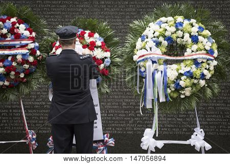 NEW YORK - SEPT 9 2016: A man adjusts one of the ceremonial wreaths placed for the 9/11 Memorial Commemoration Service at the NYC Police Memorial on the 15th anniversary of the terror attacks.
