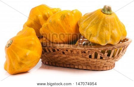 yellow pattypan squash in a wicker basket isolated on white background.