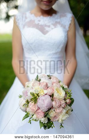 Beautiful bride is holding a wedding colorful bouquet. Beauty of colored flowers. Close-up bunch of florets. Bridal accessories. Female decoration for girl. Details for marriage and for married couple