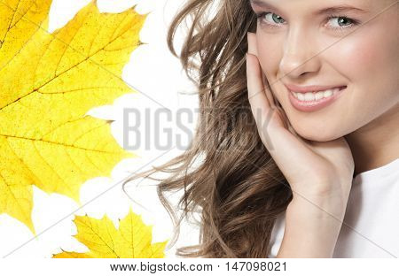 beauty closeup portrait of attractive  caucasian smiling woman  isolated on white studio shot lips toothy smile face hair looking at camera teeth hand holding yellow marple autumn leaves