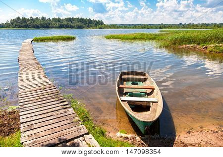 Fishing boat moored at a pier on the lake in the morning in summer sunny day
