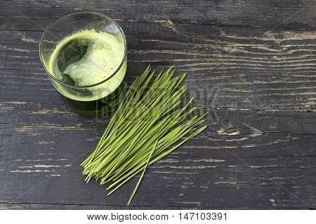 Wheat grass juice on dark wood background