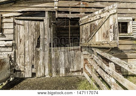 Old wool shed with old rusty door hinges and nails with weathered textured boards
