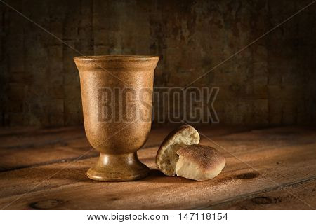 Wine goblet and bread as symbols of Communion on wooden table