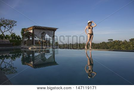 young woman walking by the pool, soaking in sun