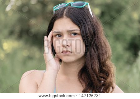 Portrait of a teen girl thinking about a problem on the nature