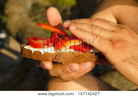 Young man holding sandwich in sunny day. Selective focus