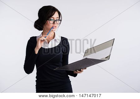 Young Caucasian woman wearing a dark blue dresst and and a white shirt, holding a ring binder folder and pen. Isolated on light background