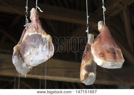 hams hang from very old wooden beams in Ghent Meat Hall