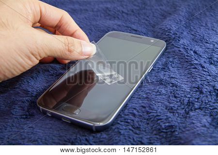 cleaning mobile phone screen by adhesive clear tape. Before apply the smart phone screen protect flim
