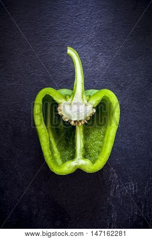 Cross section of a green bell pepper on dark bacground from above