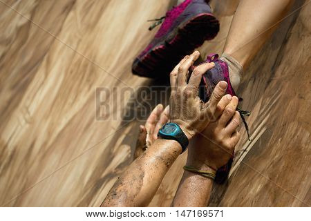 Mud race runners help when overcoming hindrances